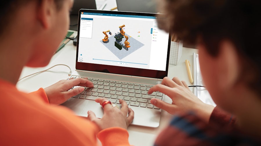 Two engineers look at a simulation of industrial robot arms on Process Simulate Collaborate software