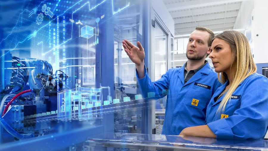 Two people observe a virtual factory superimposed on a manufacturing line representing the use of industrial IoT solutions for operational efficiency