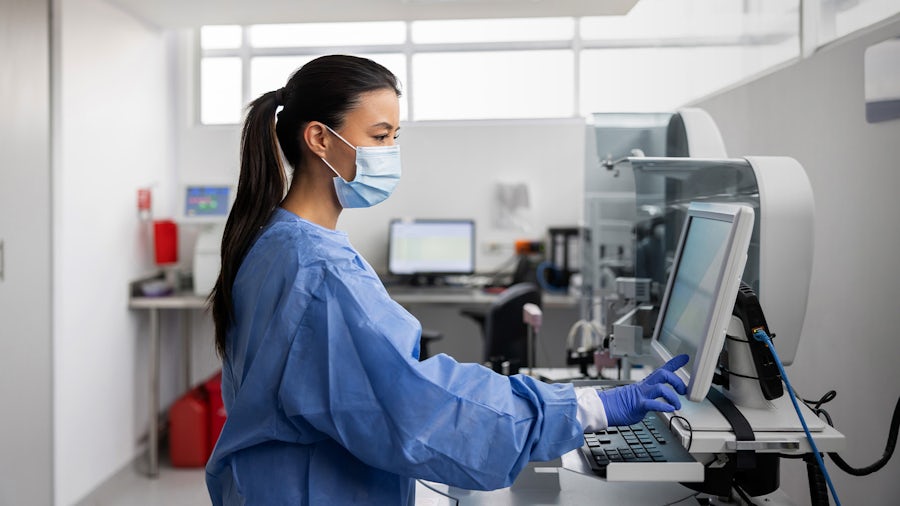 Medical professional wearing protective gear pushing a button on a monitor ensuring medical device design control.