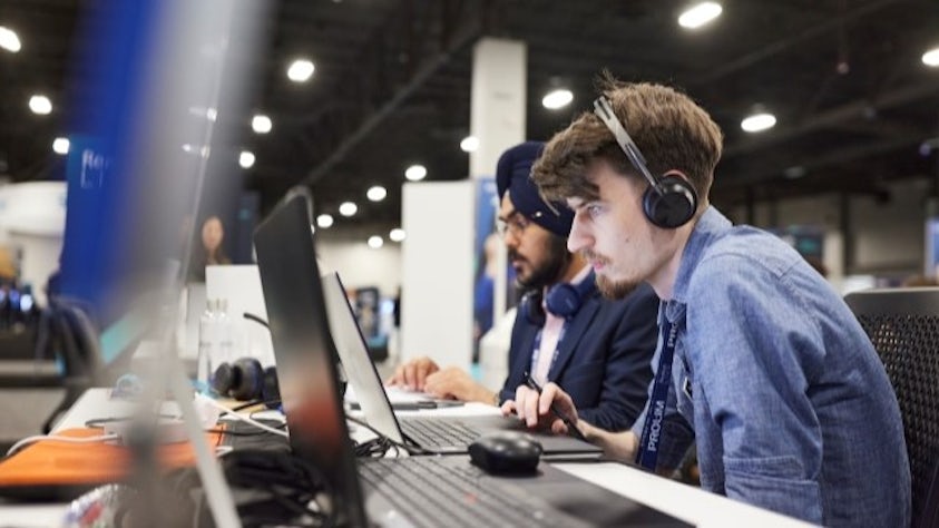 Two students sitting at a desk looking at their computers.