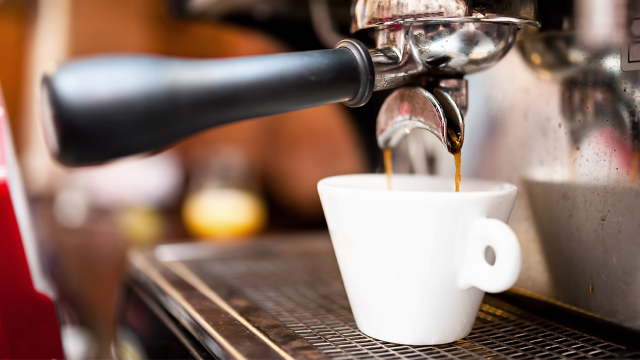 Una cafetera gotea en una taza blanca.