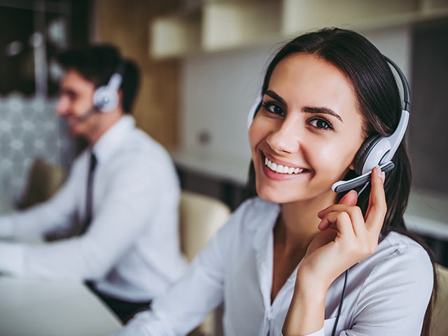 Support center employees with headsets assist customers.