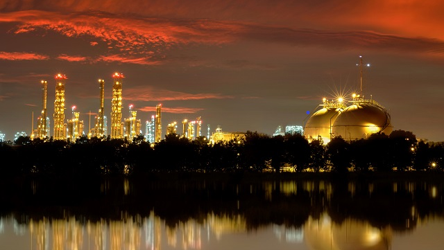 A skyline view of a city in the background with a factory in the foreground.