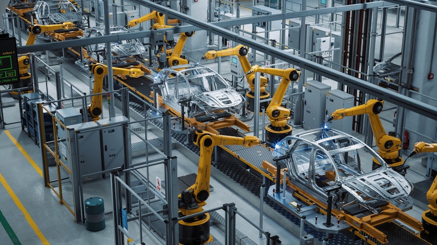 Chassis being welded with robotic arms on an assembly line in an automotive smart factory