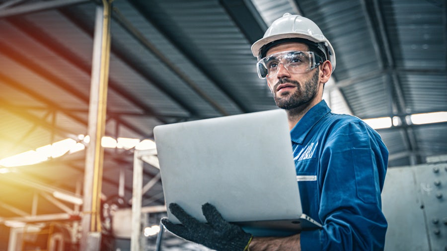 Un ingegnere controlla il software di gestione del ciclo di vita del servizio (SLM) sul suo laptop in fabbrica.