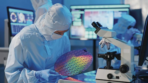 Worker examining a semiconductor wafer disk