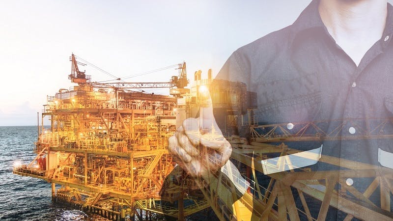 Engineer pointing his finger over the background of an oil and gas offshore platform; concept of the oil and gas digital twin