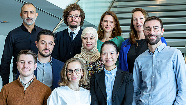 Group of diverse business people in an office smiling at the camera.