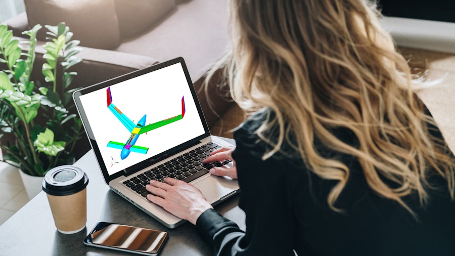 A view over the shoulder of an engineer at work using a laptop to perform aircraft structural design and analysis