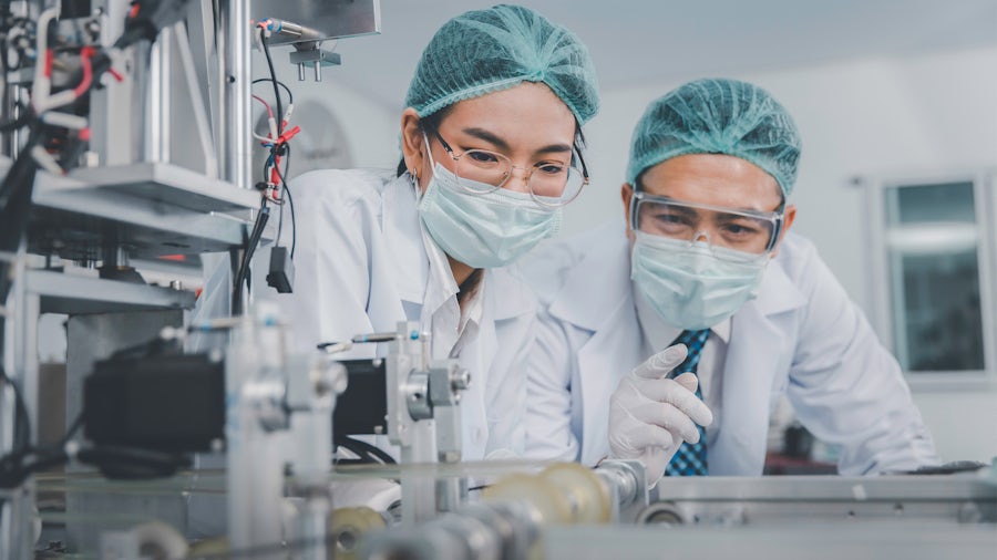 Two engineers looking at a piece of equipment in a medical device manufacturing facility.
