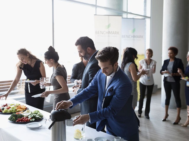 People visit a buffet table at an event.