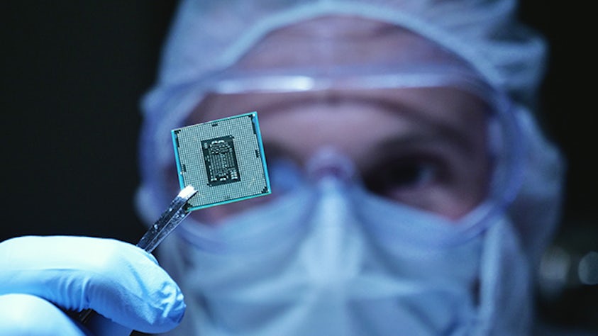Un hombre con bata de laboratorio sostiene un semiconductor.