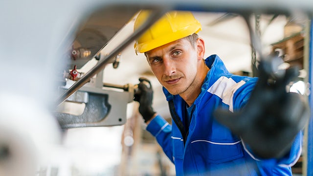 A worker in a factory looking at the quality of a part.