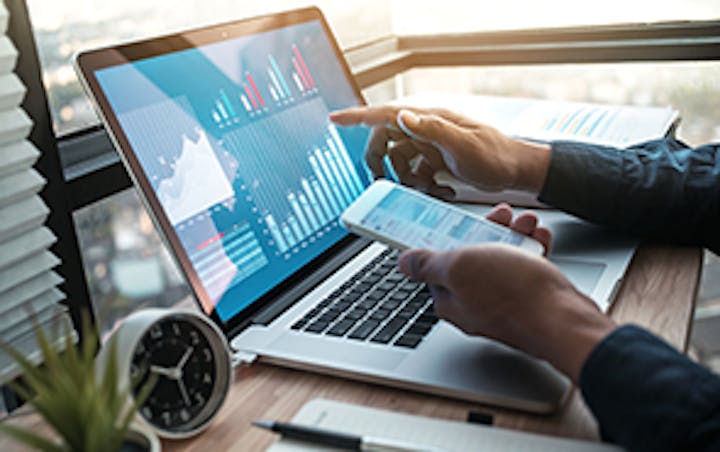 Ein Laptop-Bildschirm mit Balkendiagrammen und Armen einer Person, die ein Telefon hält und auf den Laptop zeigt.