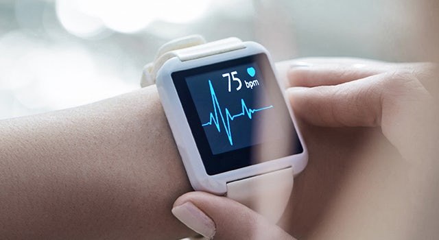 A smartwatch on a wrist displaying a heart monitor app