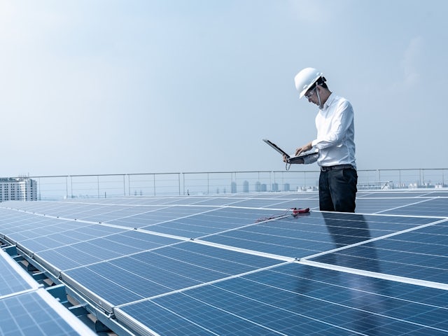 Engineer standing next to a solar farm holding a laptop computer