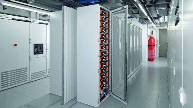 A big room containing many electrical cabinets, part of a battery energy storage system setup.