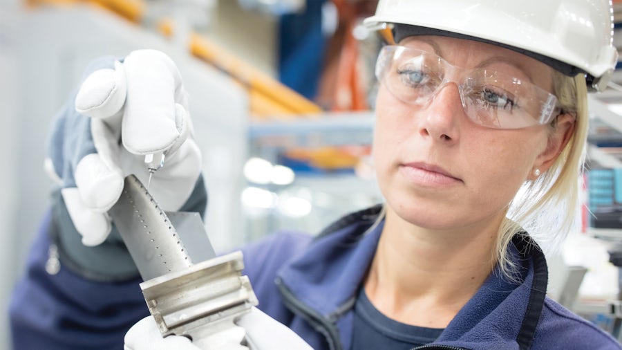 An engineer inspects a machined part