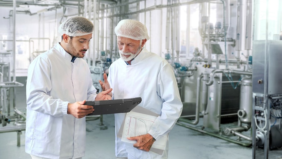 Two men, a Siemens engineer and a food plant worker, in a processing facility