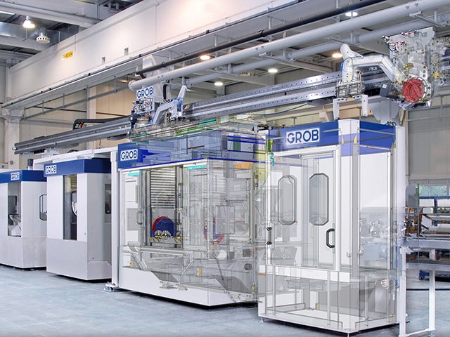 An image of a shop floor showing digital models from NX software overlayed on real models of GROB machine tools.