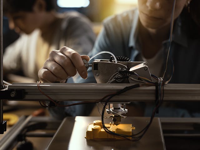 Estudiante trabajando en una impresora 3D.