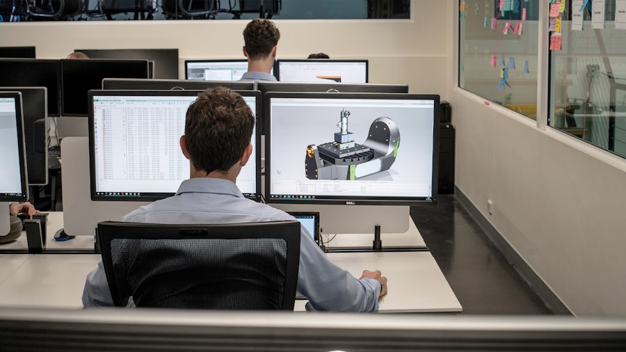 An engineer looks at a machine component service plan at his computer workstation.