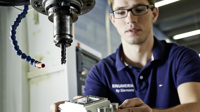 A CAM programmer placing the workpiece to be machined in CNC machine. 