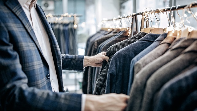 A man picks through a hanger of suit jackets
