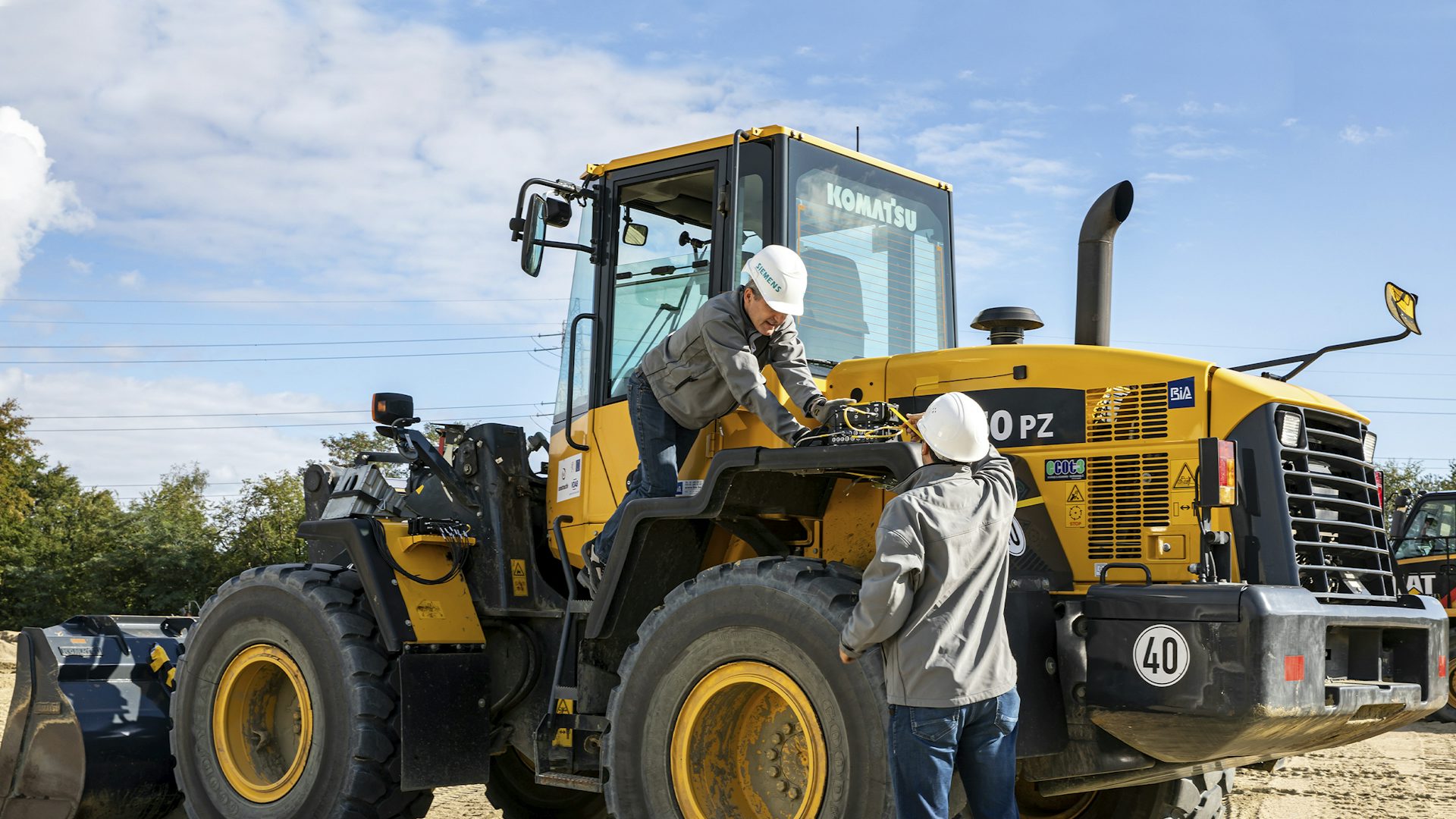 Ein paar Ingenieure beim Einrichten des Simcenter SCADAS-Hardwaregeräts auf einem Traktor.