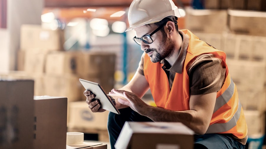 An automotive quality manager reviewing documents on a tablet using a cloud-based quality management system