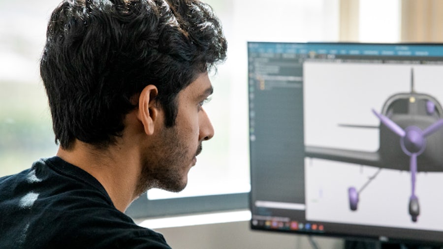 An engineer looks at an airplane model on a computer monitor – using the digital twin in aerospace manufacturing