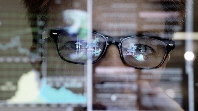 Muž v brýlích analyzuje digitální logistiku na obrazovce počítače.
