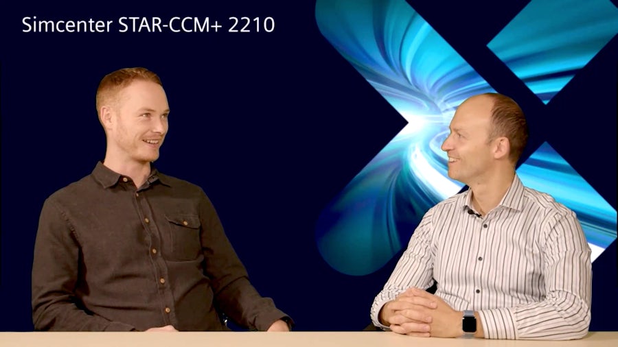 Two gentlemen sitting at a desk talking