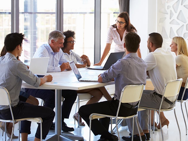 Businesswoman presenting to colleagues at a meeting in an office.