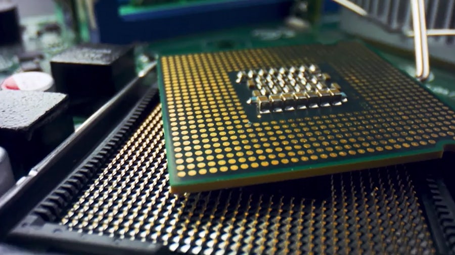 Close up image of a green and gold semiconductor piece in a circuit board.