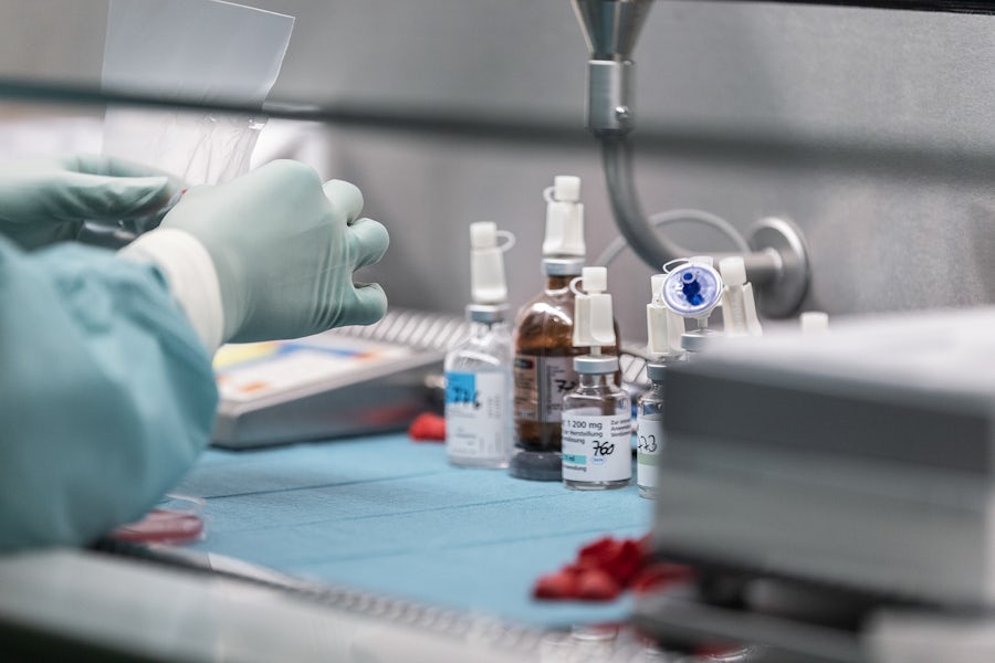 A scientist wearing protective gear works at a lab table.   