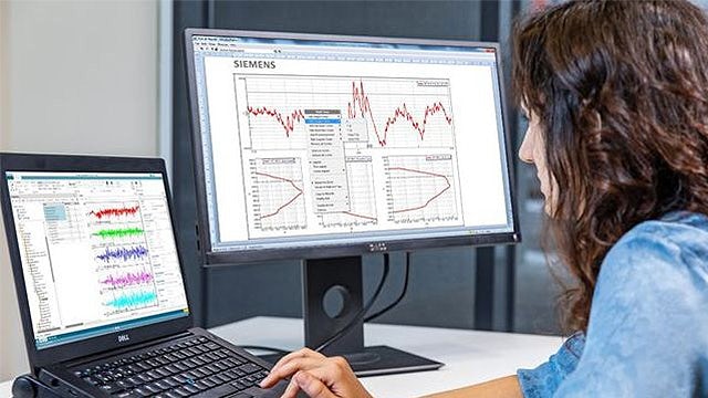 A woman reviews data reports on a laptop monitor