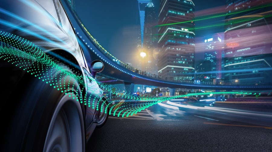 Ein Beispiel für die Komplexität einer vernetzten Infrastruktur mit einem Fahrzeug, das bei Nacht durch eine Stadt fährt und einem darüber verlaufenden Schienensystem.