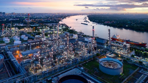 Image aérienne d'une usine pétrochimique près d'une rivière au crépuscule.