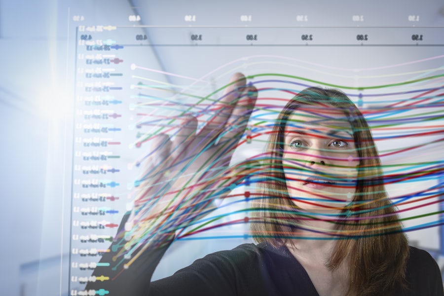 A woman analyzing a graph with vibrant lines representing data.