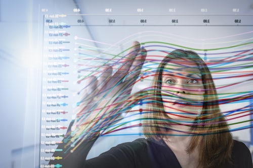 A woman analyzing a graph with vibrant lines representing data.