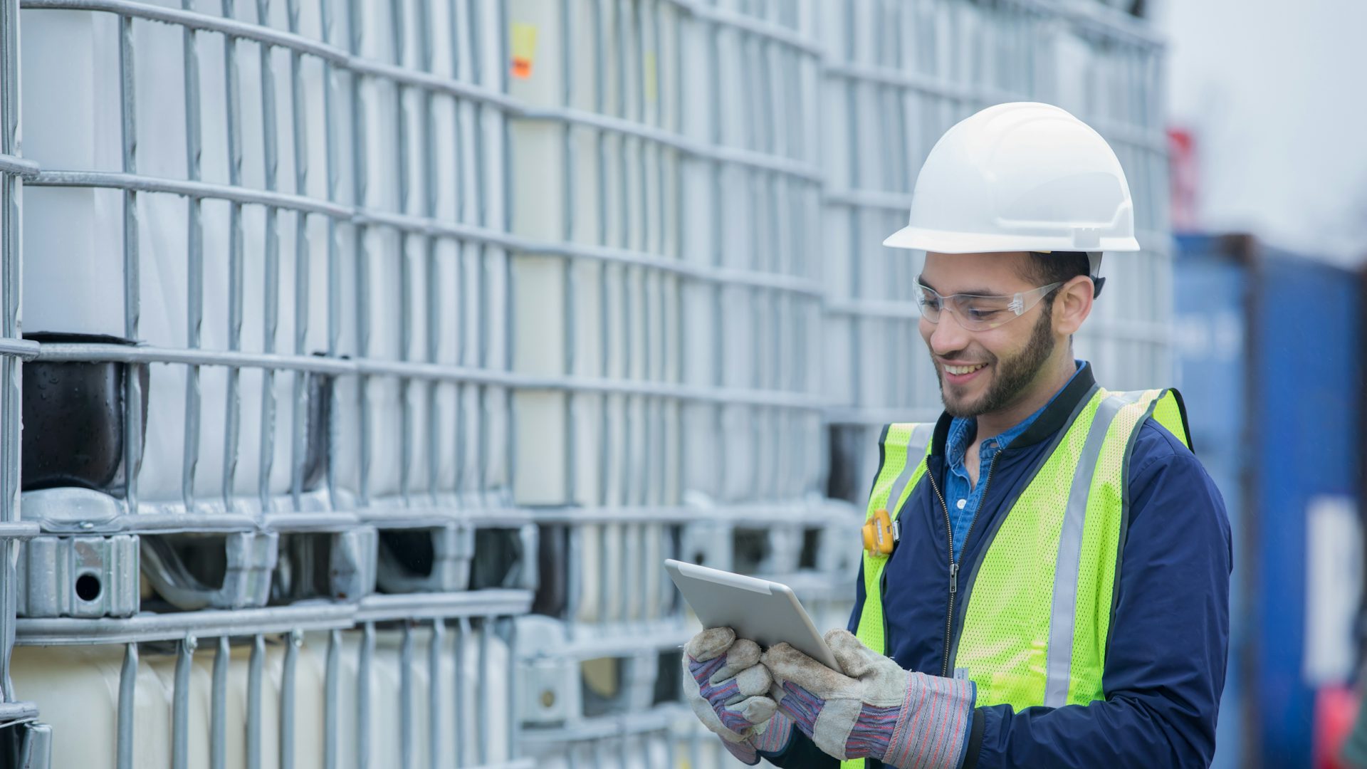 Man wearing personal protective equipment and working on a tablet.