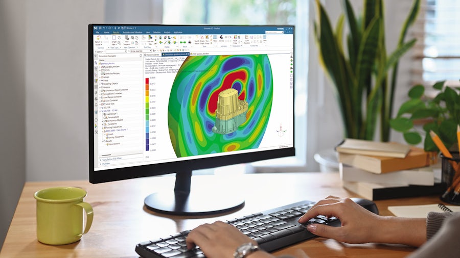 An engineer looking at a computer screen running Simcenter 3D and performing an acoustic simulation of an electric drive system.