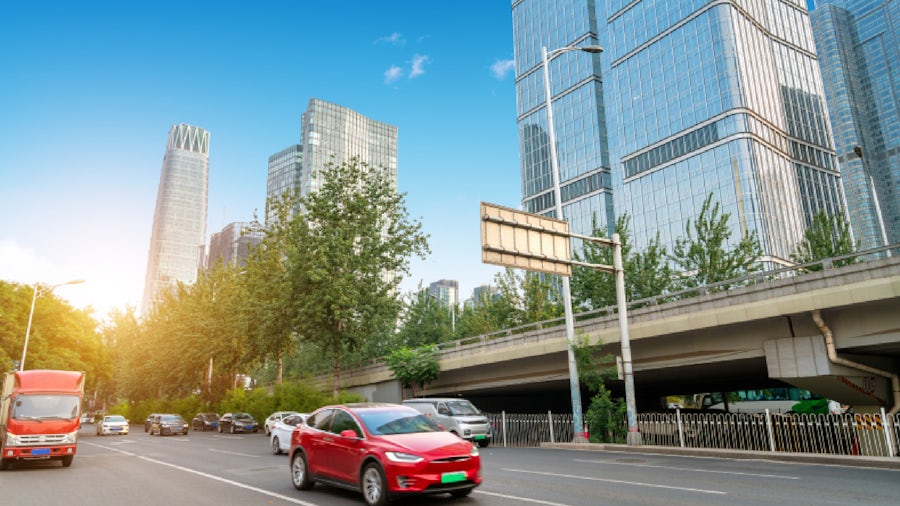 Cars on a busy city street surrounded by glass high-rise buildings.