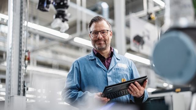 man in factory holding laptop