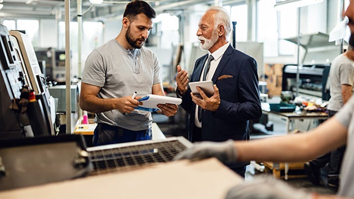 Qualitätsmanagement-Team, das eine Konformitätsprüfung in einem industriellen Umfeld durchführt und Dokumente und Maschinen auf die Einhaltung von Standards überprüft.