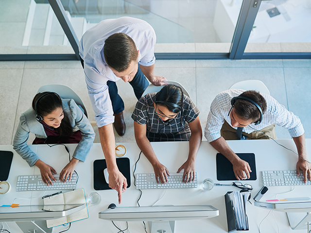An instructor teaches three students using their computers.