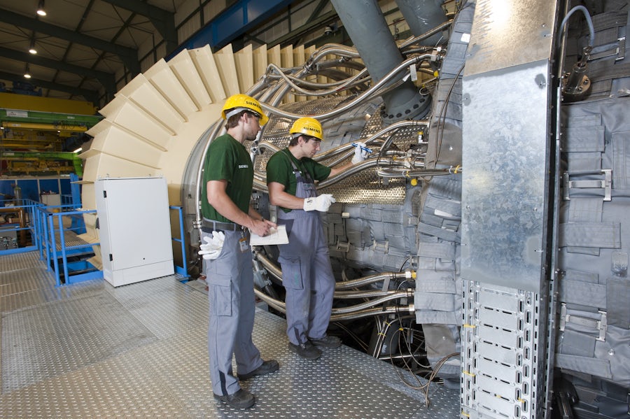 Two men performing test engineering in front of a large machine.