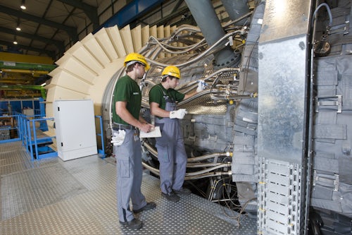 Two men performing test engineering in front of a large machine.