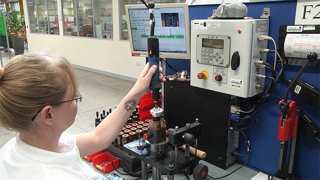 A worker uses a Norbar torque tool in a manufacturing setting.